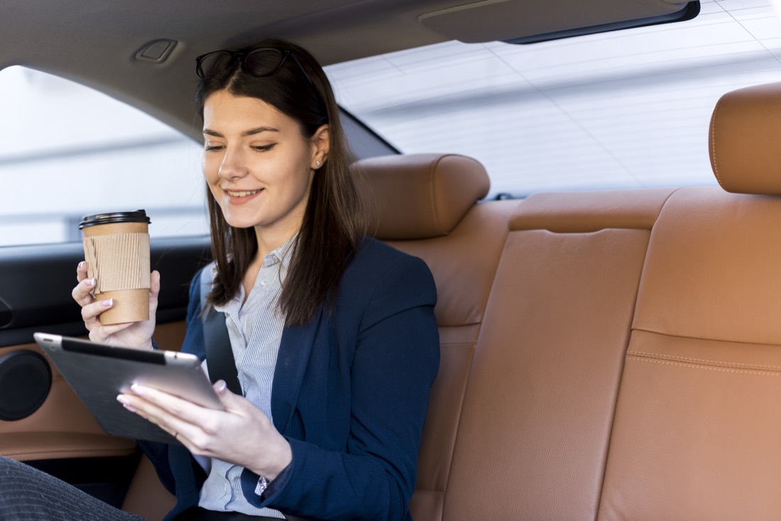 Passenger relaxing with a coffee in the back of an Airport Move taxi on a fixed-fare Heathrow to London transfer